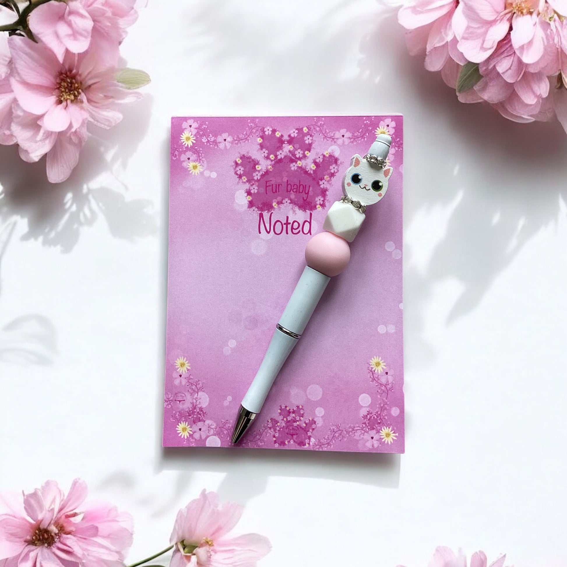 ink and white decorative beads adorning elegant white cat-themed pen"
