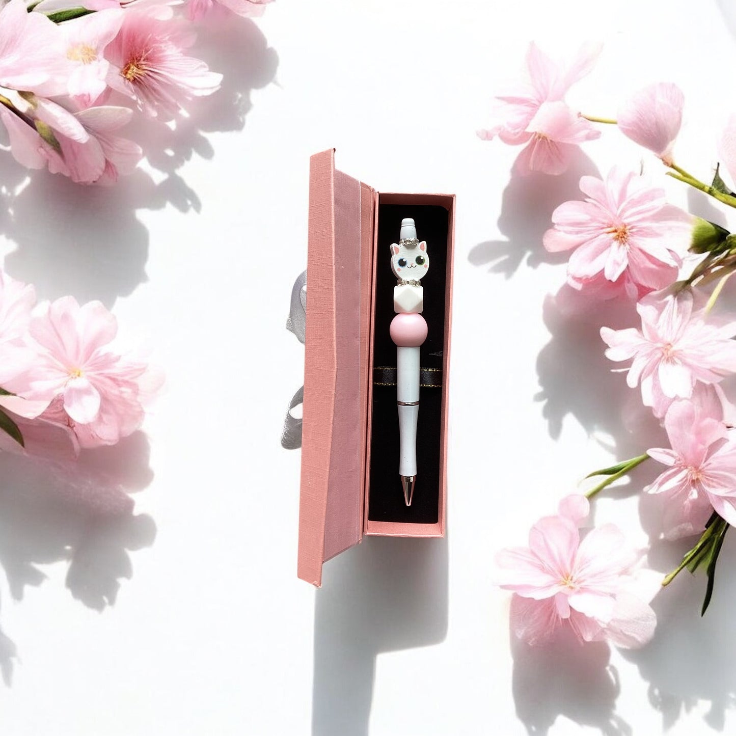 "Pink and white decorative beads adorning elegant white cat-themed pen in a presentation box"