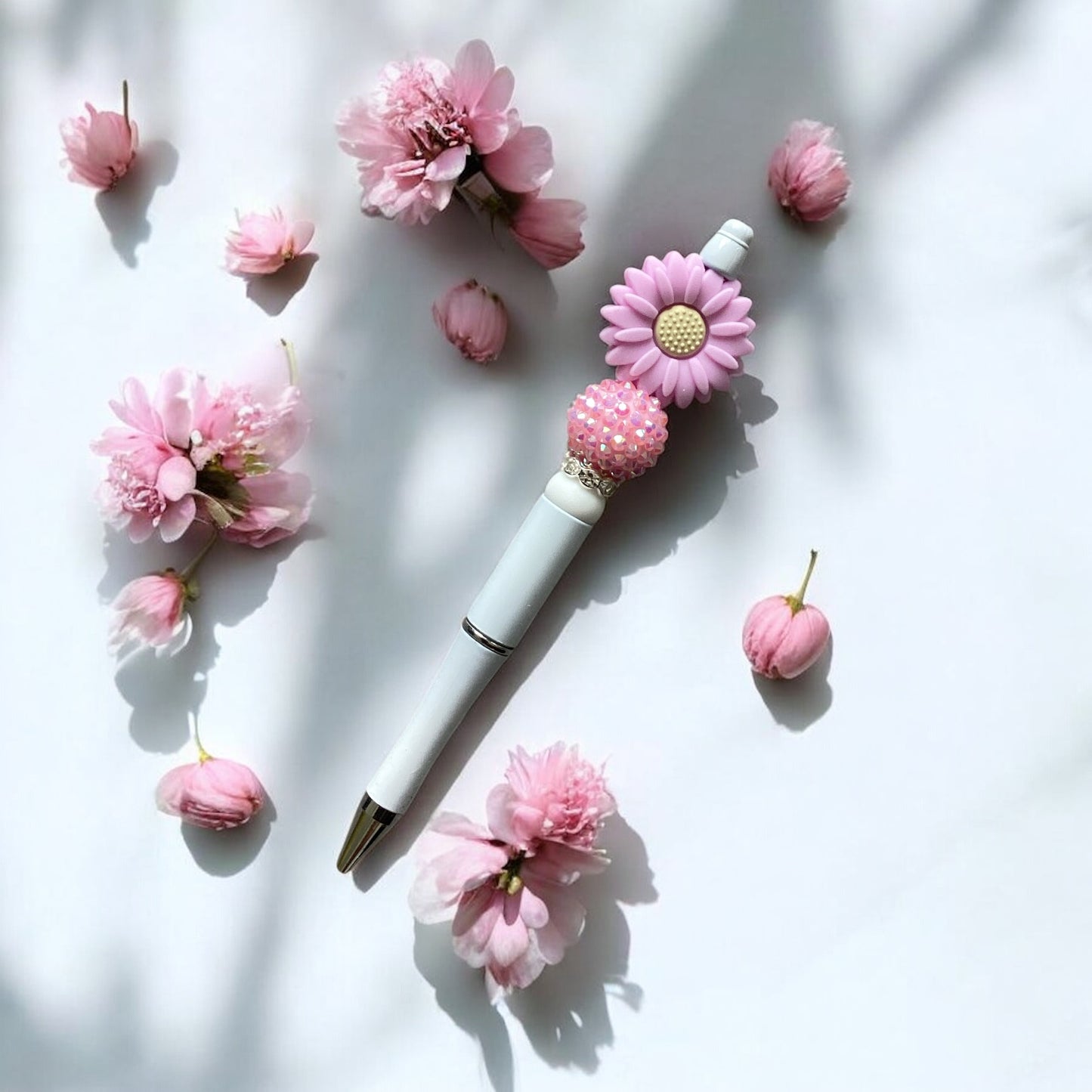 "Lilac daisy beaded pen with white casing and black ballpoint tip"